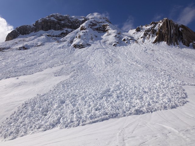 Белая лавина сходит с гор солнечным днем