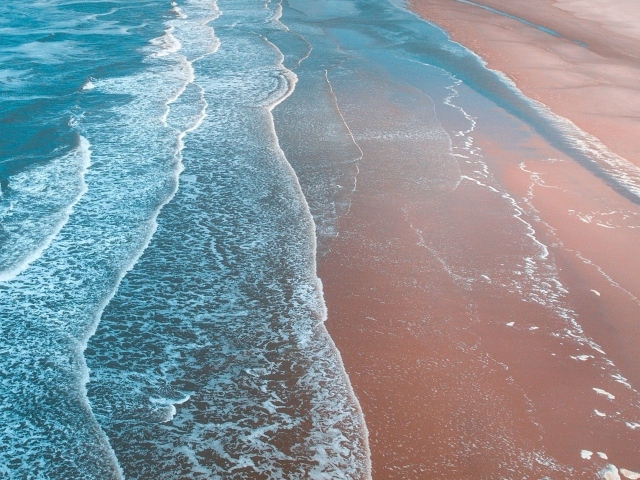 Нежные белые волны омывают песчаный берег океана 