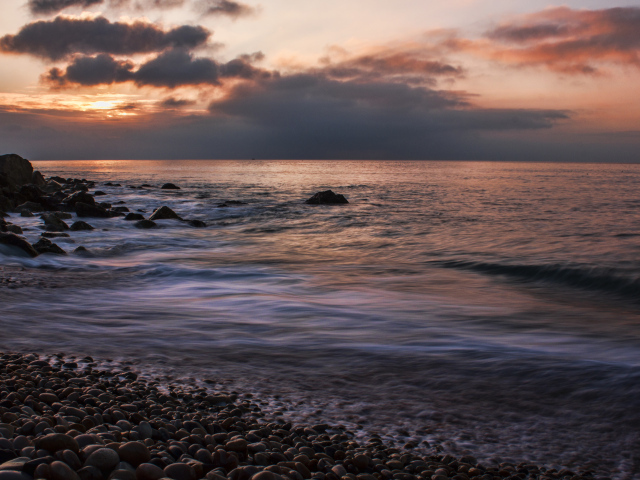 Мелкие камни на берегу моря на закате