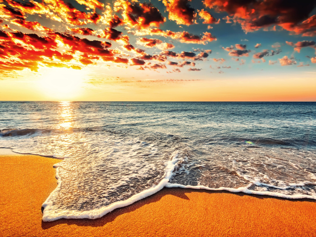 Белая морская пена на оранжевом песке под красивым небом