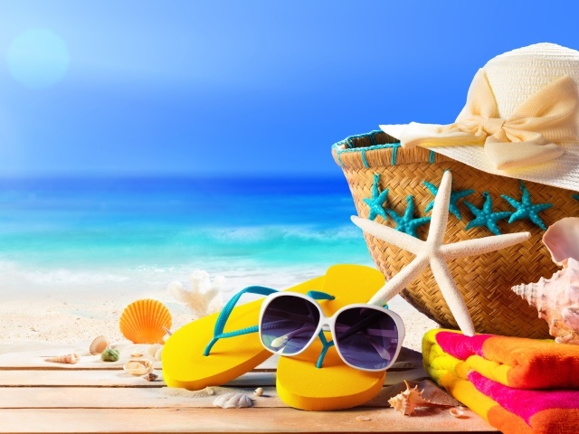 Сумка, шляпа, очки, сланцы и полотенце на пляже с ракушками летом