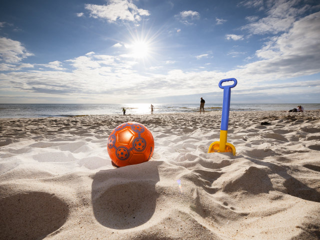 Игрушки на белом песке в лучах яркого солнца летом