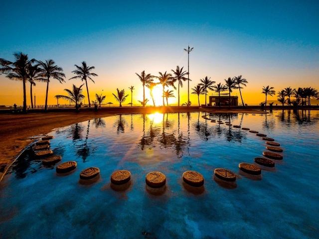 Закат солнца на тропическом пляже на фоне бассейна