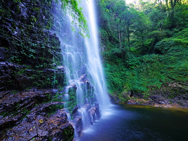 Быстрый водопад стекает по мокрым камням со скалы
