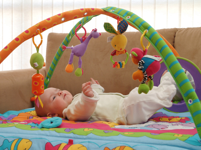 Грудной малыш играет с игрушками