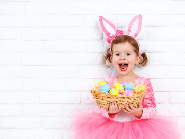 Красивая маленькая девочка в костюме с корзиной крашеных яиц 