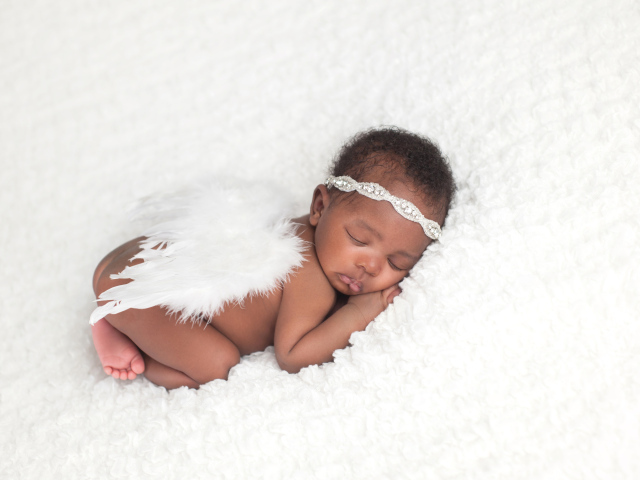 Темнокожий младенец спит с крыльями ангела