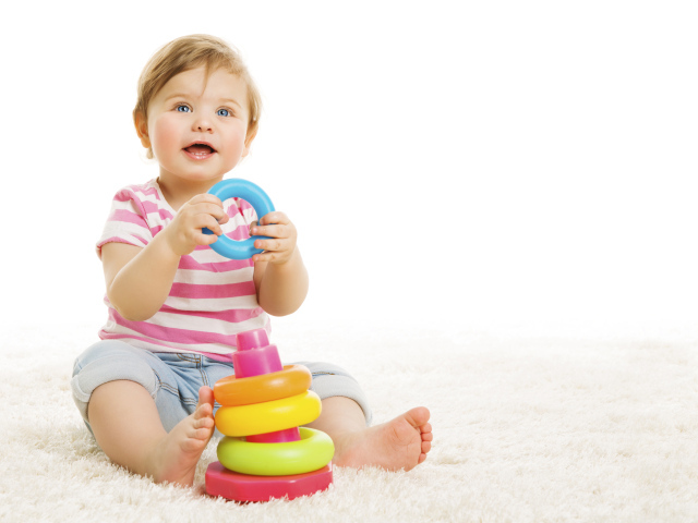 Голубоглазый маленький мальчик с игрушкой на белом фоне