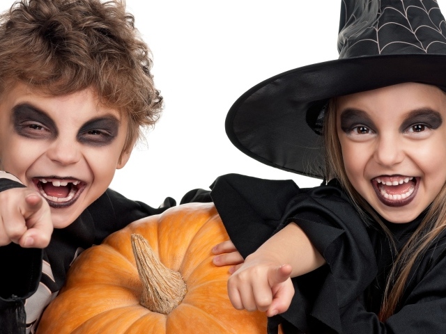 Мальчик и девочка с тыквой на белом фоне в костюмах на Хэллоуин 