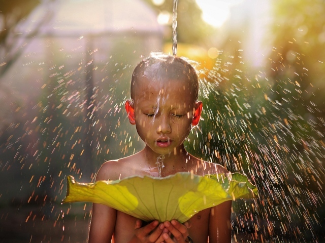Маленький мальчик азиат умывается водой