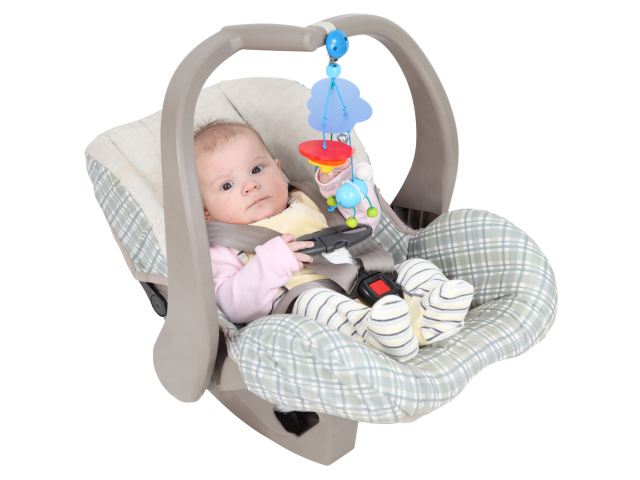 Маленький грудной ребенок в автомобильном кресле на белом фоне