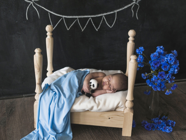 Маленький ребенок спит в деревянной кровати 