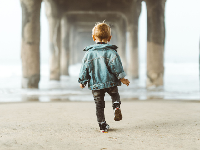 Маленький мальчик в джинсовой куртке спиной