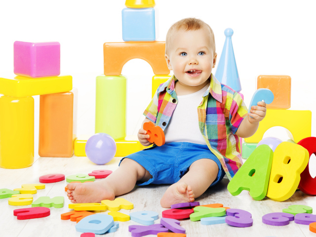 Маленький мальчик играет с разноцветными игрушками 