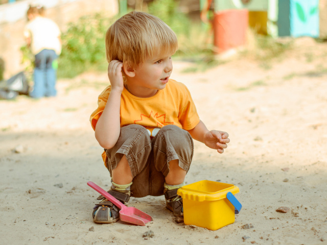 Маленький мальчик играет на песке 