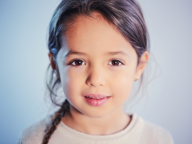 Маленькая кареглазая девочка на сером фоне