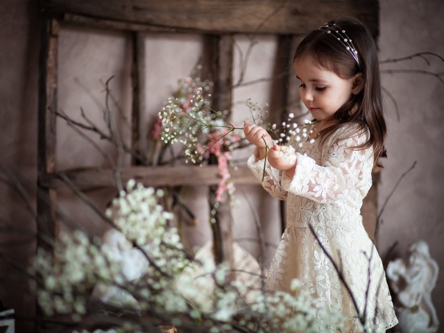 Маленькая девочка в красивом платье с белыми цветами в руке
