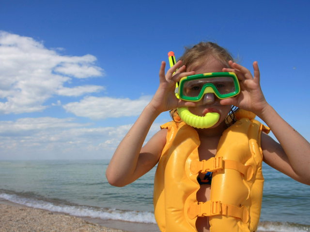 Маленькая девочка в маске и спасательном жилете на море