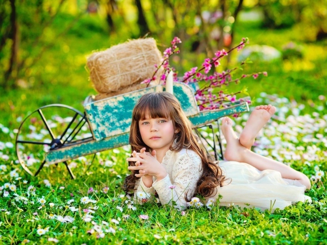 Маленькая девочка лежит на зеленой траве 