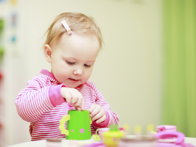 Маленькая девочка играет с посудой 