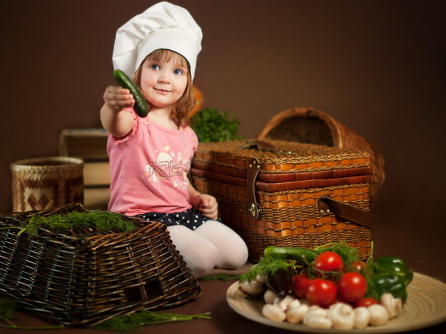 Маленькая девочка сидит на столе с корзинами и овощами