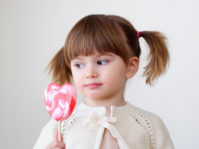 Маленькая девочка с большой конфетой на палочке