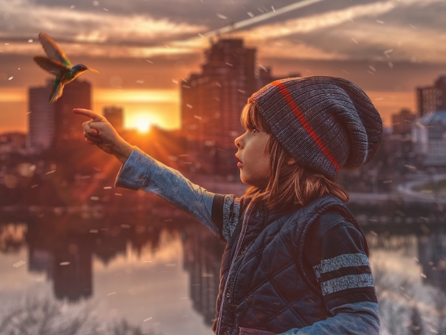 Маленькая девочка с птицей колибри на фоне города