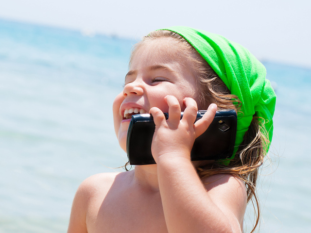 Маленькая девочка с телефоном на пляже