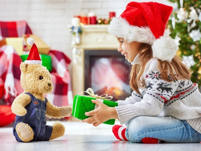 Маленькая девочка с медвежонком Тедди у елки с подарками на Новый год