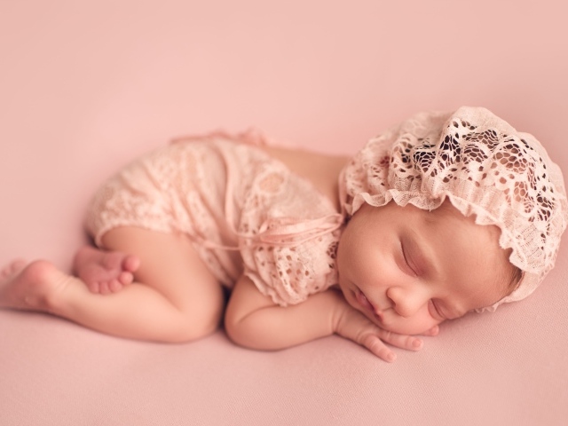 Маленькая новорожденная девочка в розовом костюме 