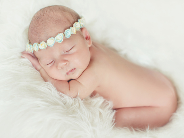 Маленький спящий ребенок на меховом покрывале