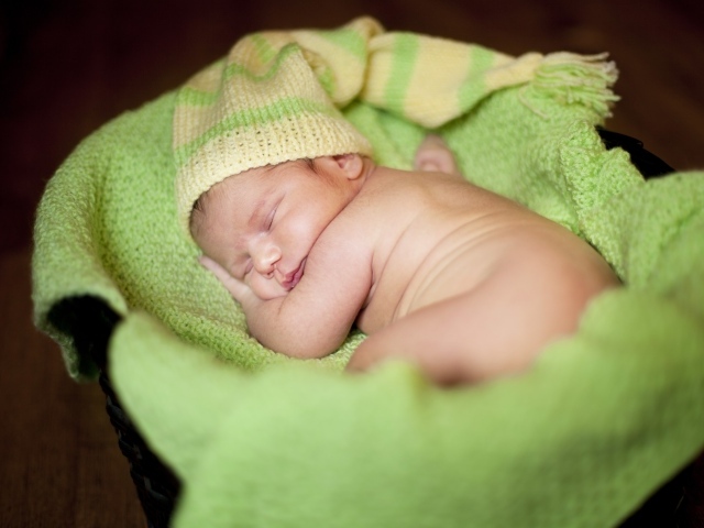 Маленький спящий грудной ребенок на зеленом покрывале 