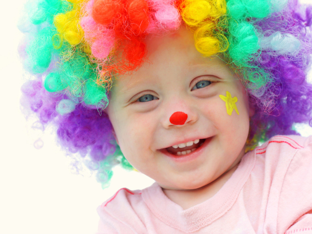 Маленький улыбающийся мальчик в костюме клоуна на белом фоне