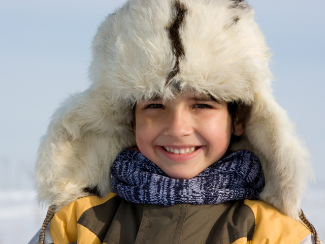 Маленький улыбающийся мальчик в теплой шапке зимой