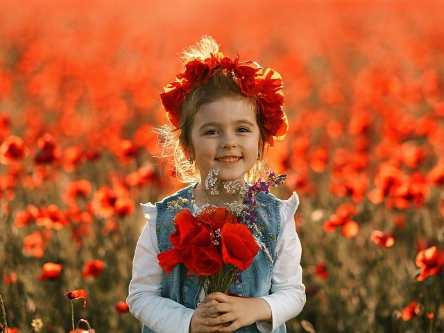 Маленькая улыбающаяся девочка с венком из красных маков на голове и букетом в руках