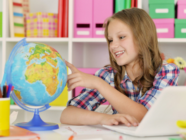 Улыбающаяся девочка школьница с глобусом