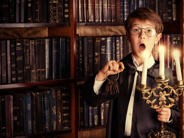 Удивленный мальчик с подсвечником со свечами в библиотеке