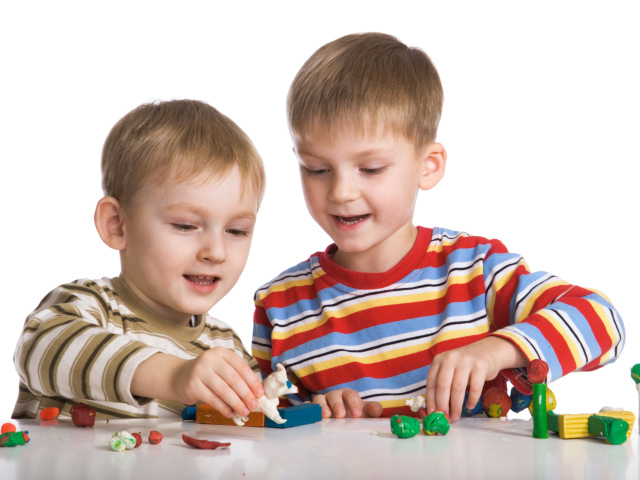 Два мальчика играют в игрушки на белом фоне