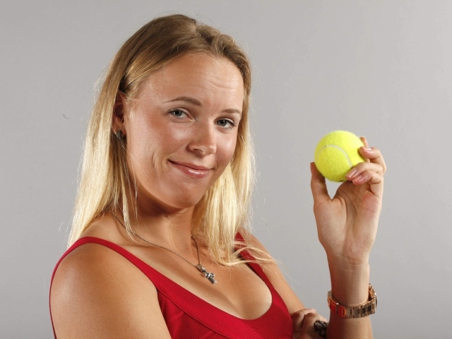 Датская теннисистка Каролина Возняцки с мячиком в руке на сером фоне