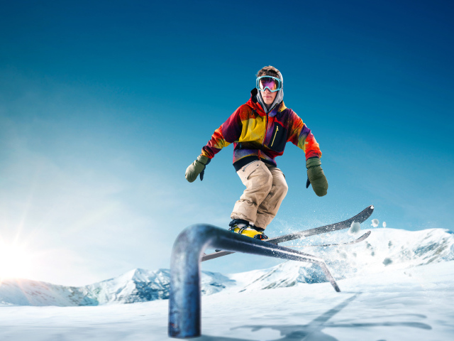 Молодой парень катается на лыжах на заснеженной горе в лучах солнца