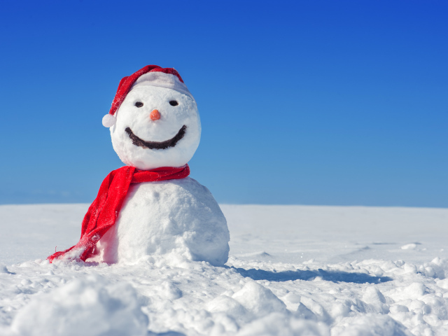 Веселый снеговик в красной шапке на белом снегу