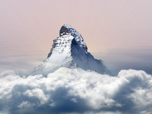 Заснеженная верхушка горы в белых облаках 