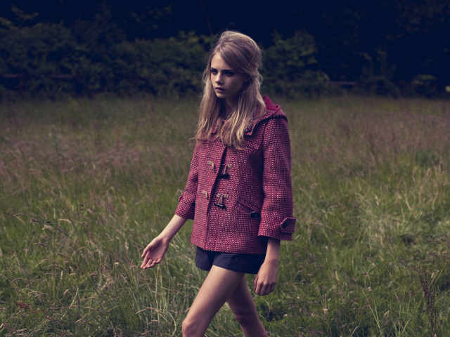 Актриса Кара Делевинь идет по траве в пальто 