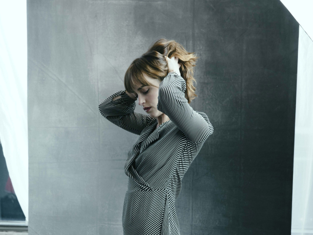 Актриса Дакота Джонсон в платье с руками в волосах