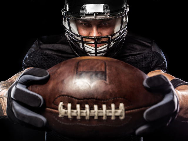 Американский футболист с мячом на черном фоне