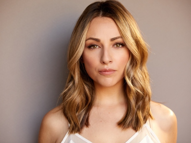 Красивая блондинка Никки Поснер на сером фоне 