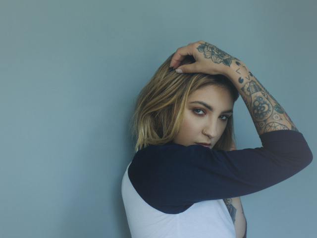 Красивая девушка стоит с татуировками на руке 