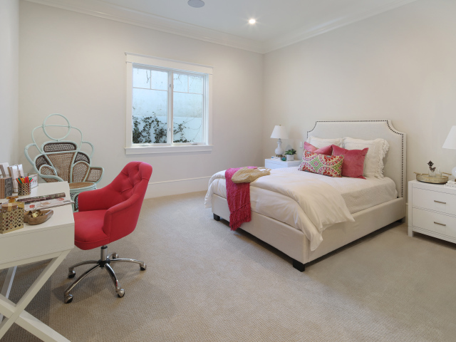 Спальня в светлых тонах с кроватью и столом с красным креслом