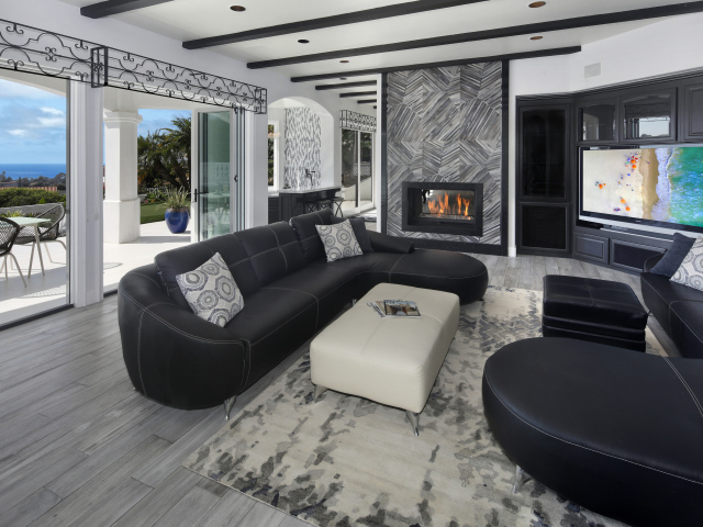 Большая просторная гостиная с черными кожаными диванами, телевизором и камином 