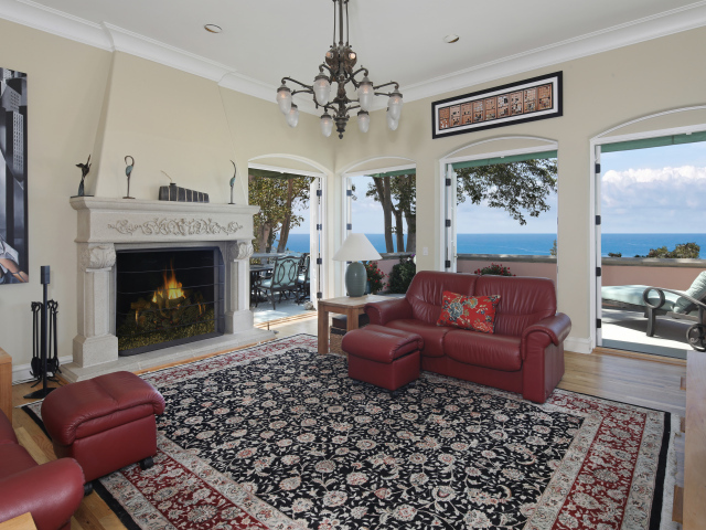 Гостиная с кожаным диваном, большими окнами и камином 